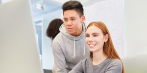 Two young business people or students together in the computer workshop