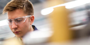 a young man using machinery in a work environment as an apprentice