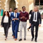 four young people walking outside an office in business wear