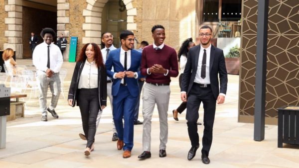 four young people walking outside an office in business wear